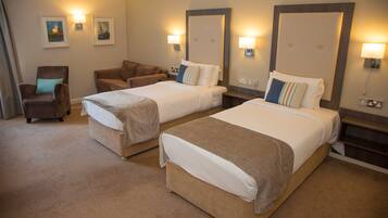A hotel room with two beds, a chair, and a sofa.