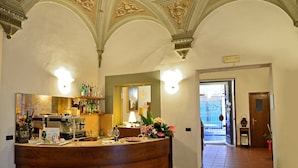 A bar area with a counter, bar stools, and a decorative mirror. There is a sign with text, a coffee machine, and a variety of bottles on shelves. - Hotel Vasari (Florence)