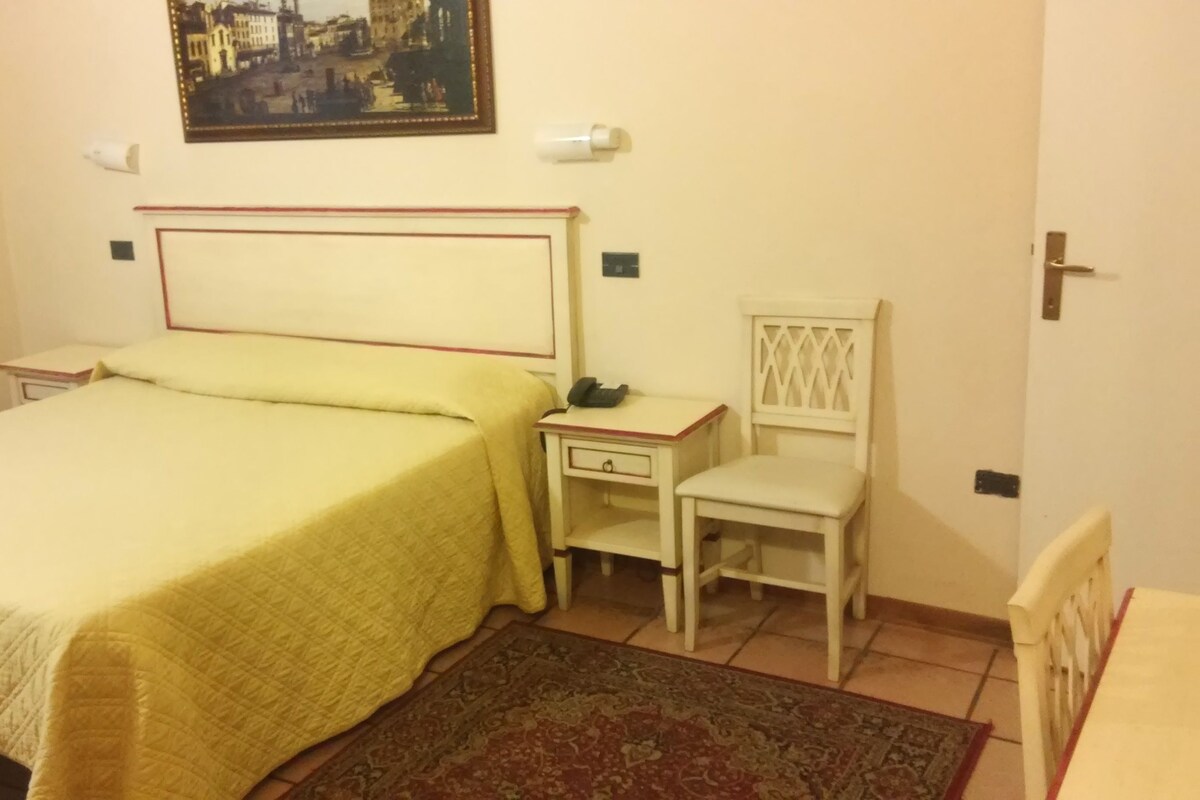 Une chambre à coucher avec un lit, une table de chevet, une chaise et un tableau au mur.