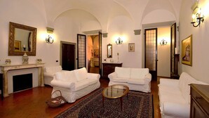 A spacious living room with white sofas, a fireplace, and a large mirror. - Hotel Vasari (Florence)