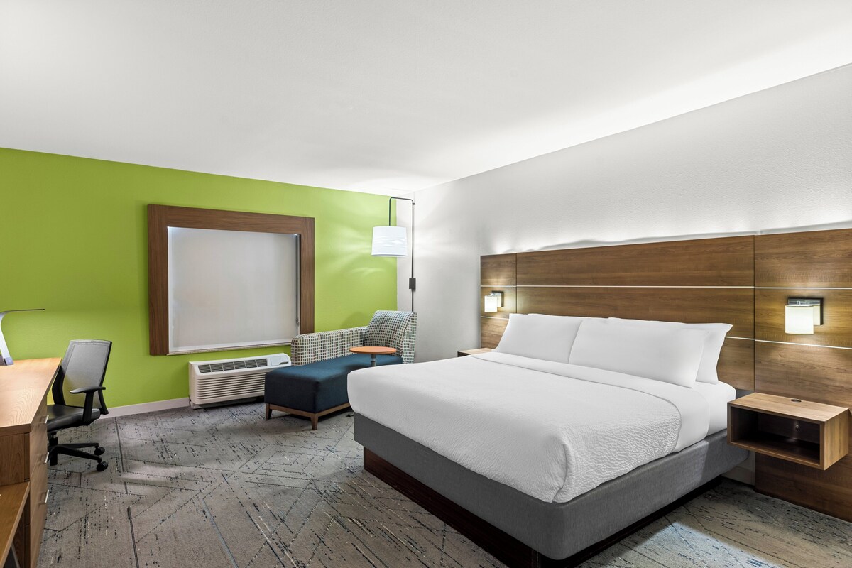 A hotel room with a large bed, a desk with a chair, a small table, and a couch.