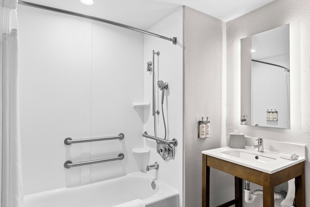 A modern bathroom with a bathtub, shower, and sink.