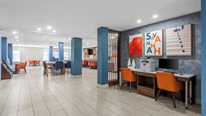 A modern library with multiple tables and chairs, a large screen, and artwork on the walls. - Holiday Inn Express and Suites Savannah - Midtown by IHG (Savannah)