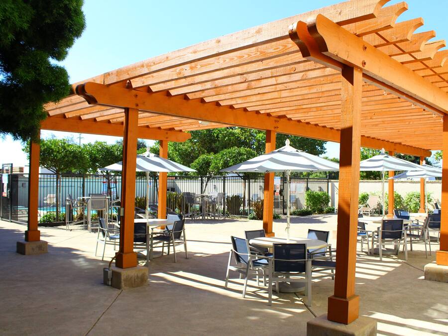 An outdoor patio area with wooden pergolas, tables, and chairs.