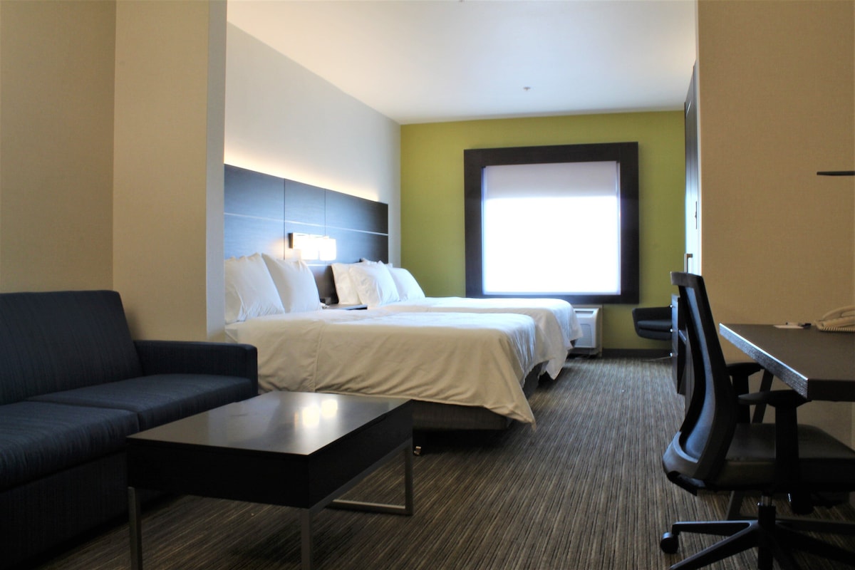A hotel room with a bed, a sofa, a desk, and a chair.