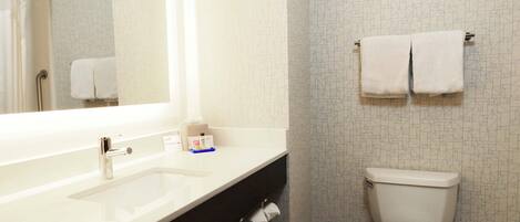 A bathroom with a white sink, mirror, and toilet. There are two towels hanging on the wall.