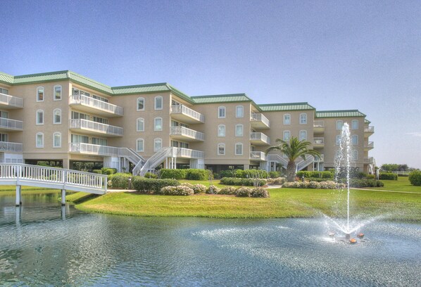 A multi-story hotel with balconies, a central fountain, and a bridge over a water feature. - Hodnett Cooper St Simons Grand - 3 Bedroom (St. Simons Island)