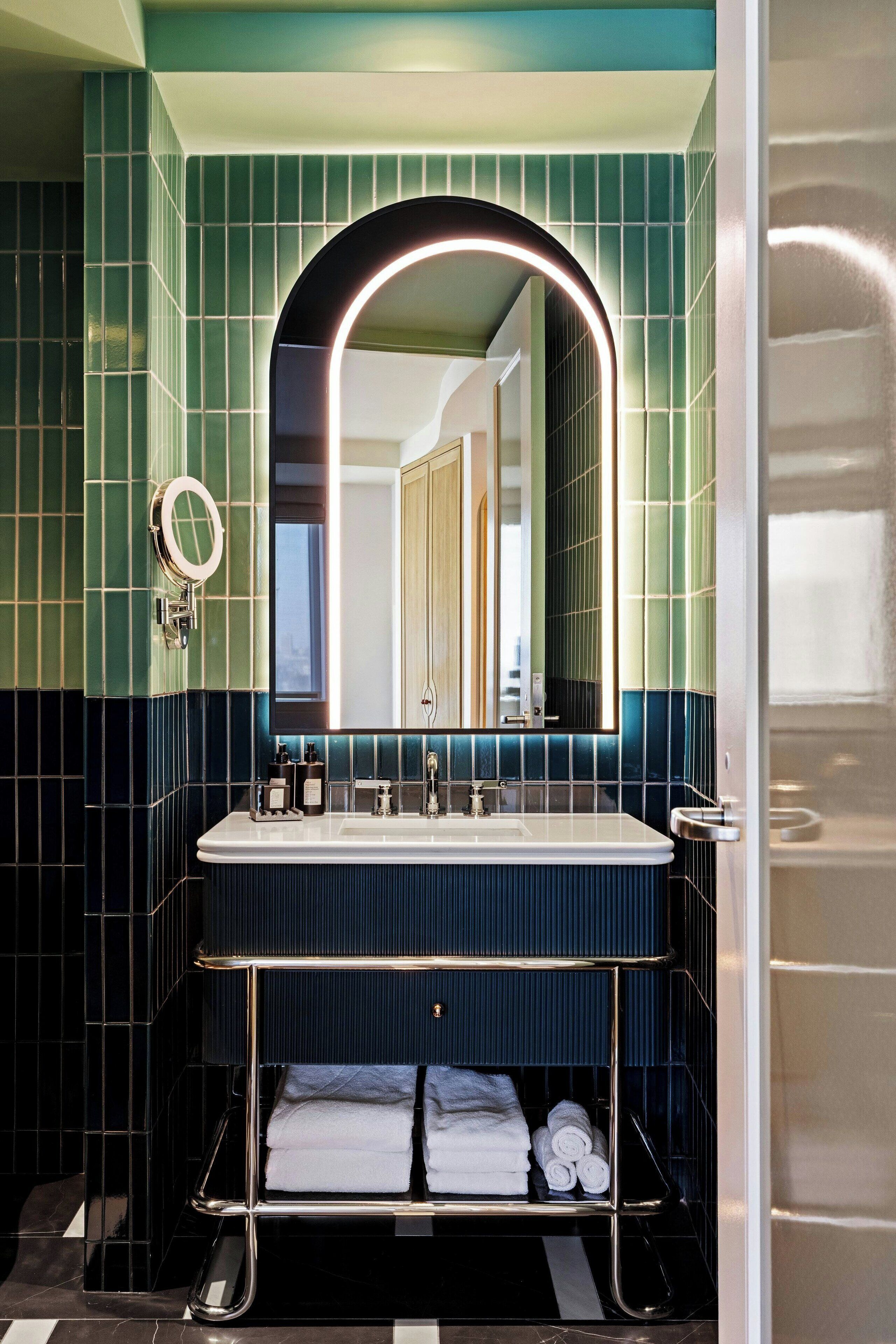 A bathroom with a large mirror, a sink, and a towel rack.