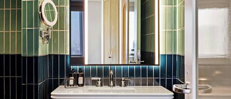 A bathroom with a large mirror, a sink, and a towel rack.