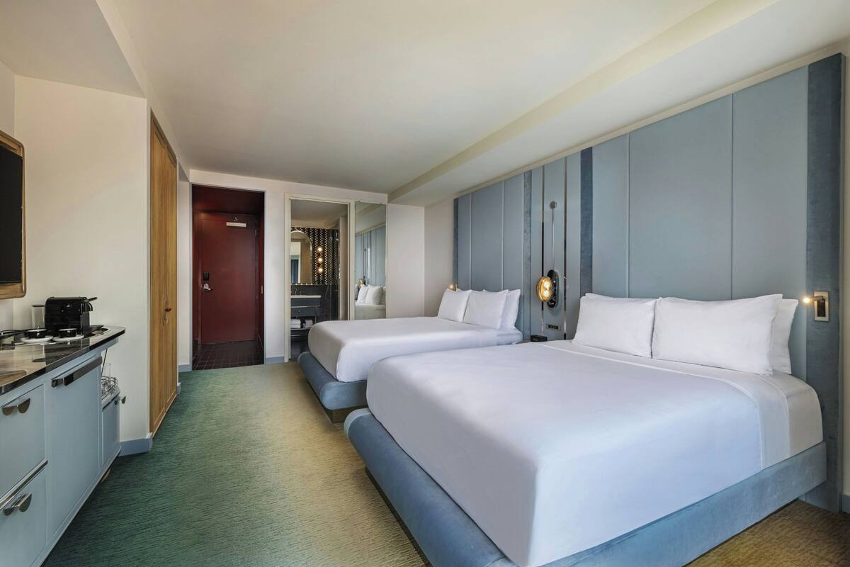 Habitación de hotel con dos camas, kitchenette y vestidor.