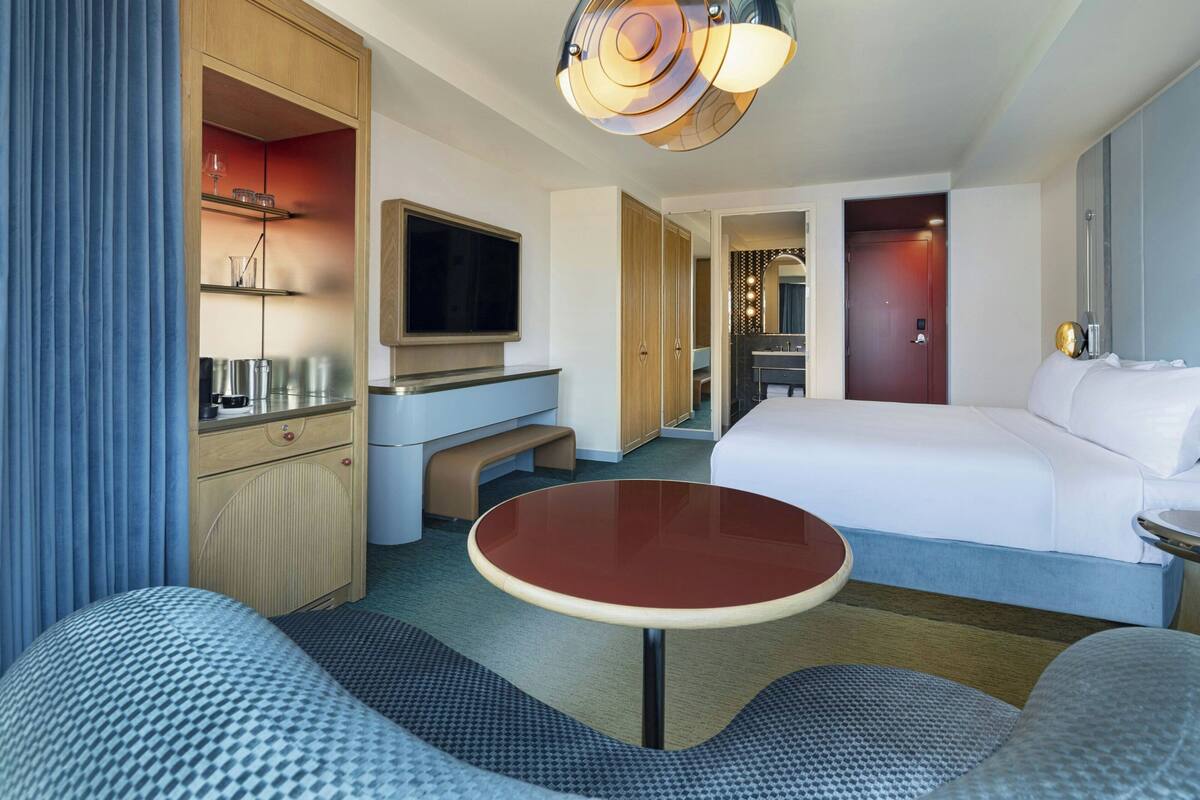 Una habitación de hotel moderna con cama, televisión, escritorio y zona de estar.