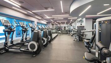 A modern gym with treadmills, elliptical machines, and weightlifting equipment.