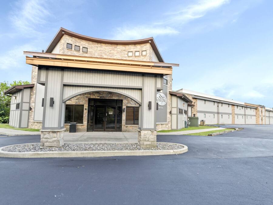 A modern building with a stone facade, a prominent entrance, and a parking lot.