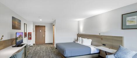 A hotel room with a bed, a desk, a chair, a TV, and a couch.