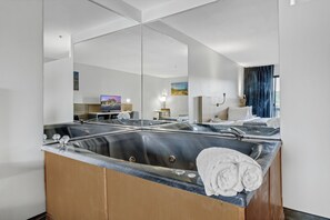 A modern bathroom with a large mirror, a bathtub, and a sink.