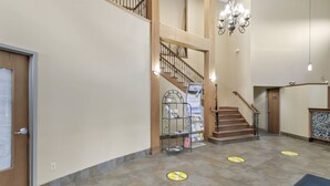 A spacious lobby with a staircase, a reception desk, and a chandelier. - Waterbird Lakeside Inn (Chesterton)
