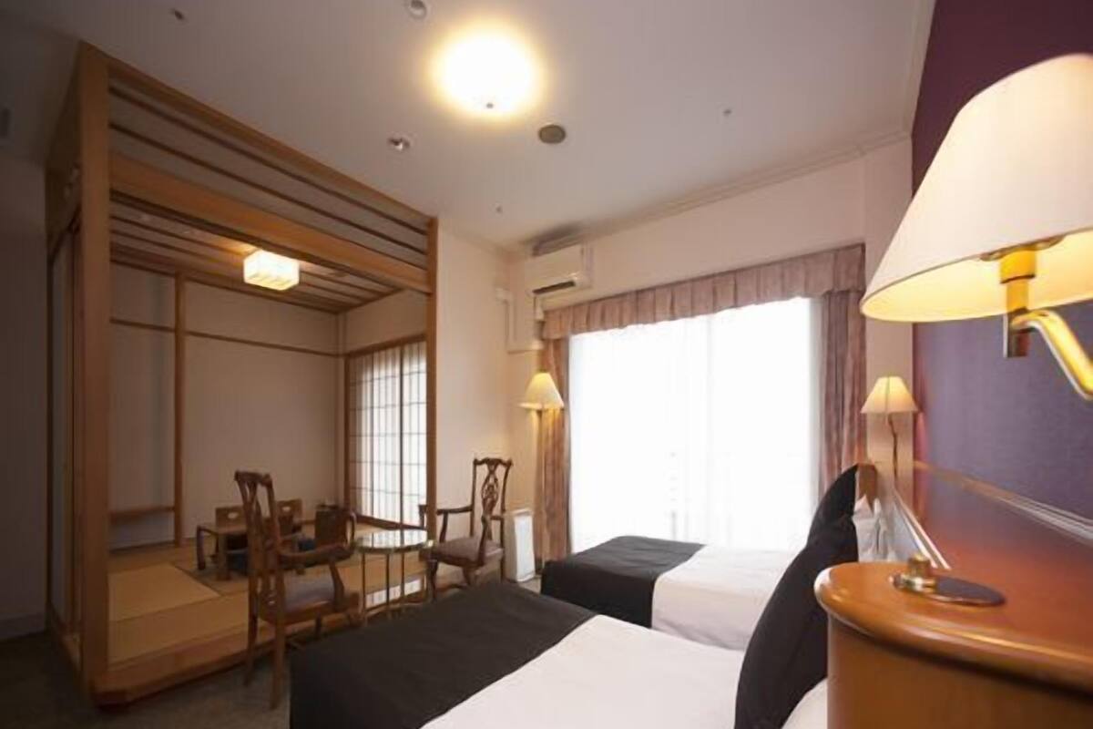 Een hotelkamer met een bed, een bureau, stoelen en een raam.