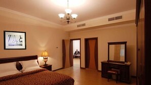 Una habitación de hotel con cama, escritorio, silla, espejo y un cuadro en la pared.