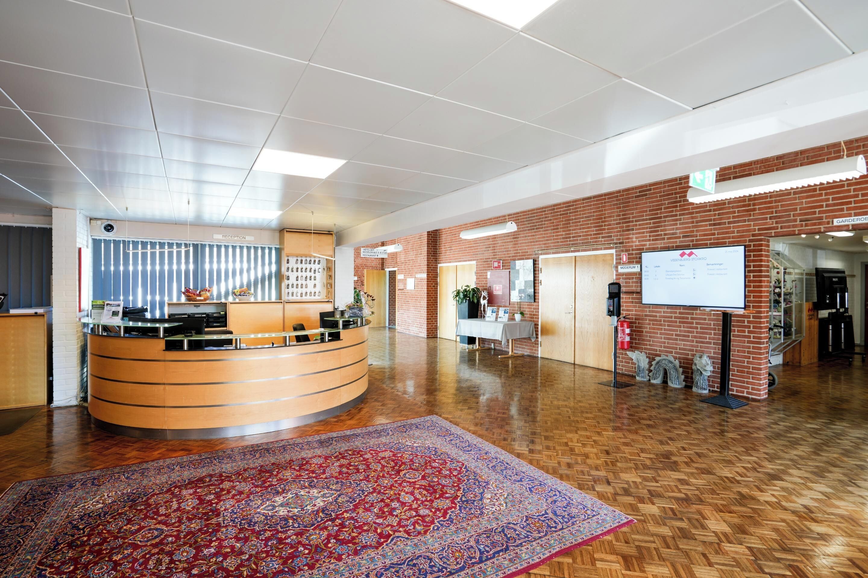 A reception area with a curved desk, a large patterned rug, and a brick wall.