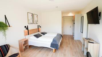 Un dormitorio moderno con una cama, mesitas de noche, un televisor y un escritorio.