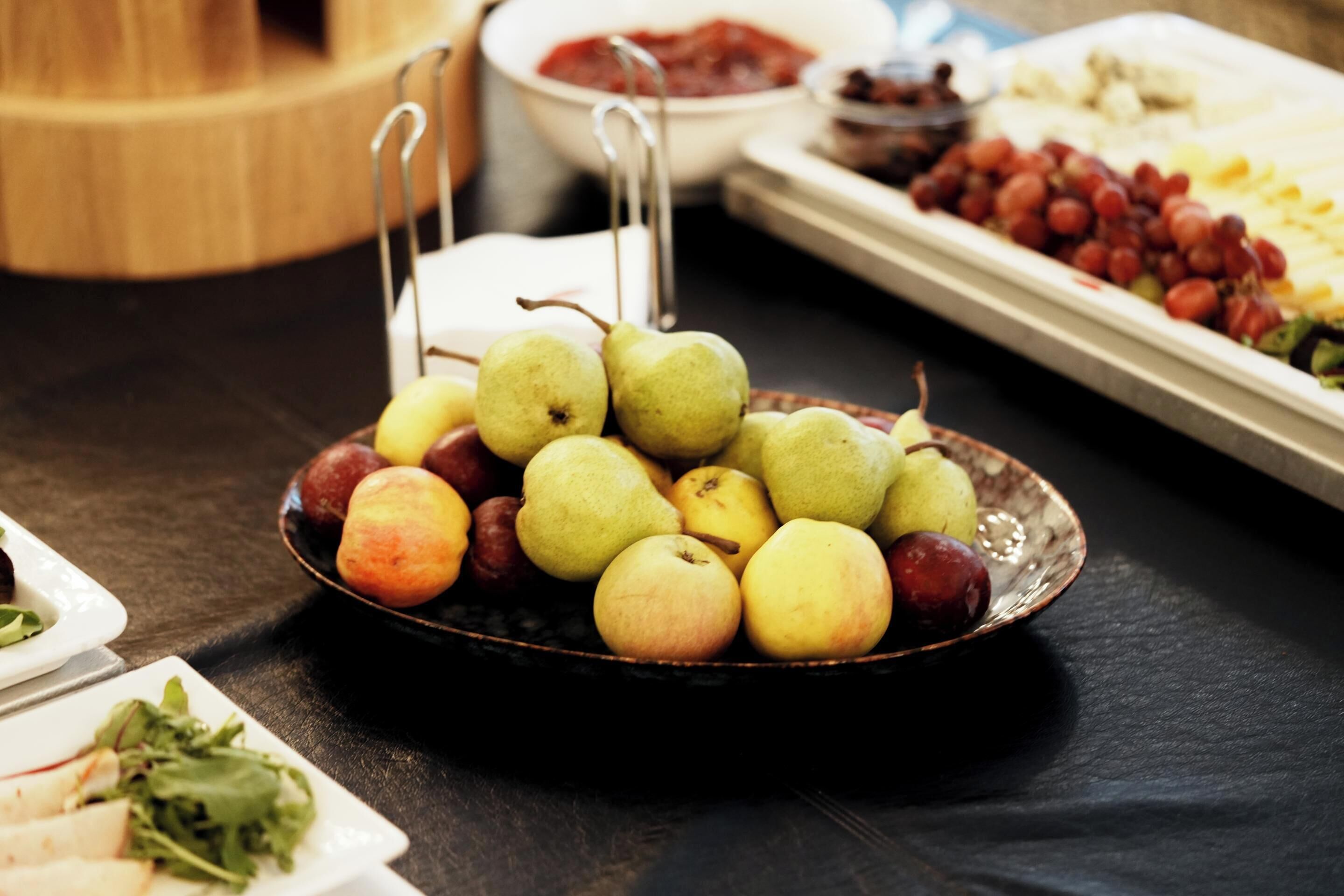 A table with a variety of fruits and vegetables, including apples and grapes.