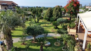 A well-maintained garden with various plants and a patio area with outdoor seating. - Hotel Damanse (Ricadi)