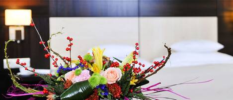 A bouquet of flowers in a white vase on a table in a hotel room.