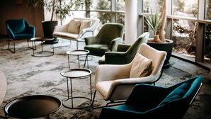 A modern lounge area with multiple seating options including armchairs and sofas, arranged around small tables. - Ruben Hotel (Zielona Gora)