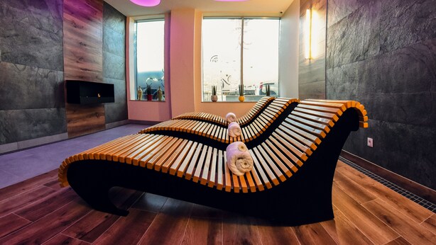 A modern spa room with a unique curved bench, large windows, and a fireplace. - Ruben Hotel (Zielona Gora)