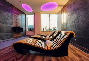 A modern spa room with a unique curved bench, large windows, and a fireplace.
