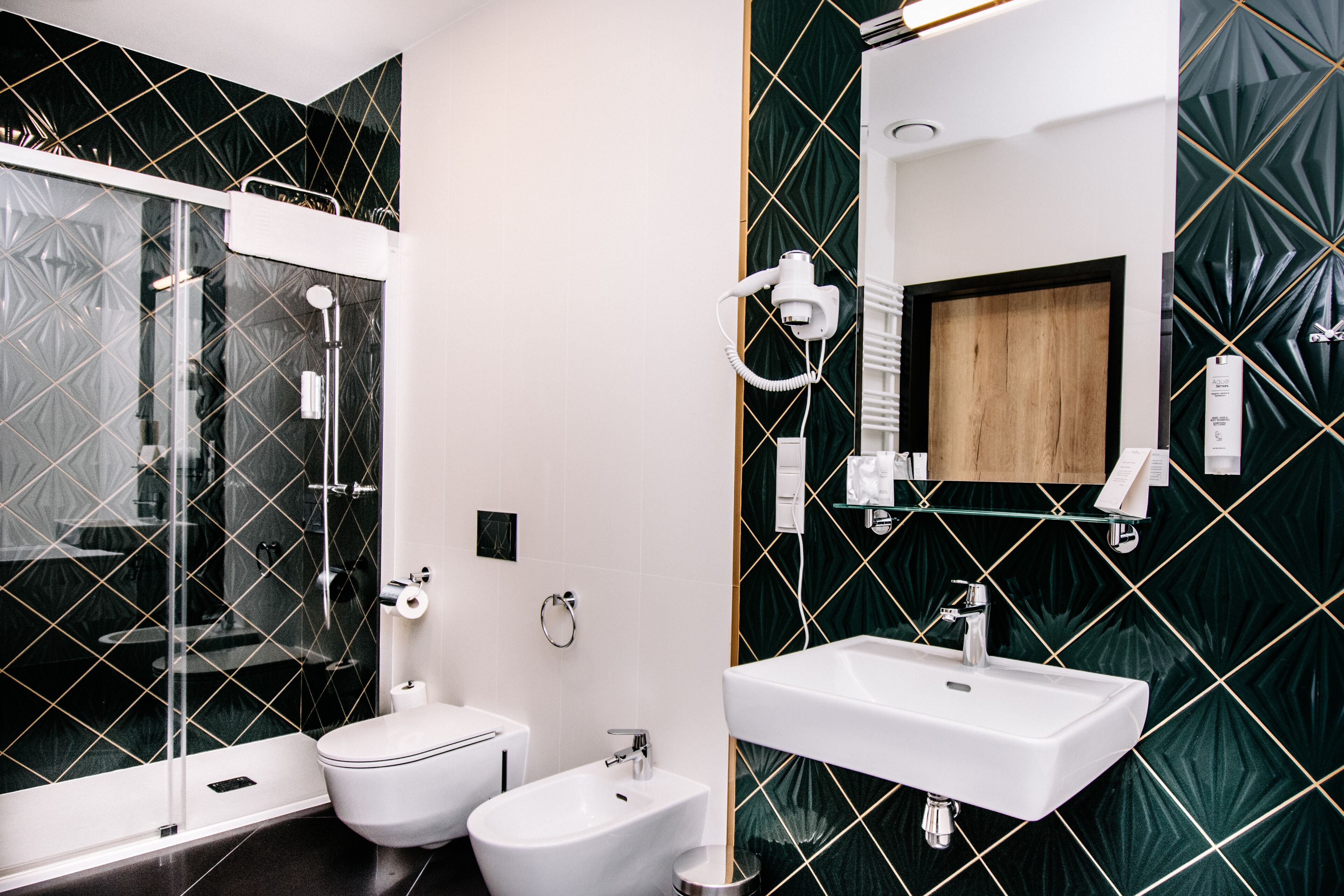 A modern bathroom with a glass-enclosed shower, a white toilet, a bidet, and a sink with a wooden vanity.