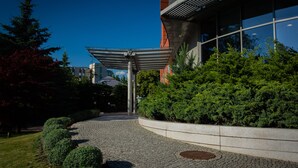 A modern building with a curved pathway, a metal canopy, and well-maintained greenery. - Ruben Hotel (Zielona Gora)