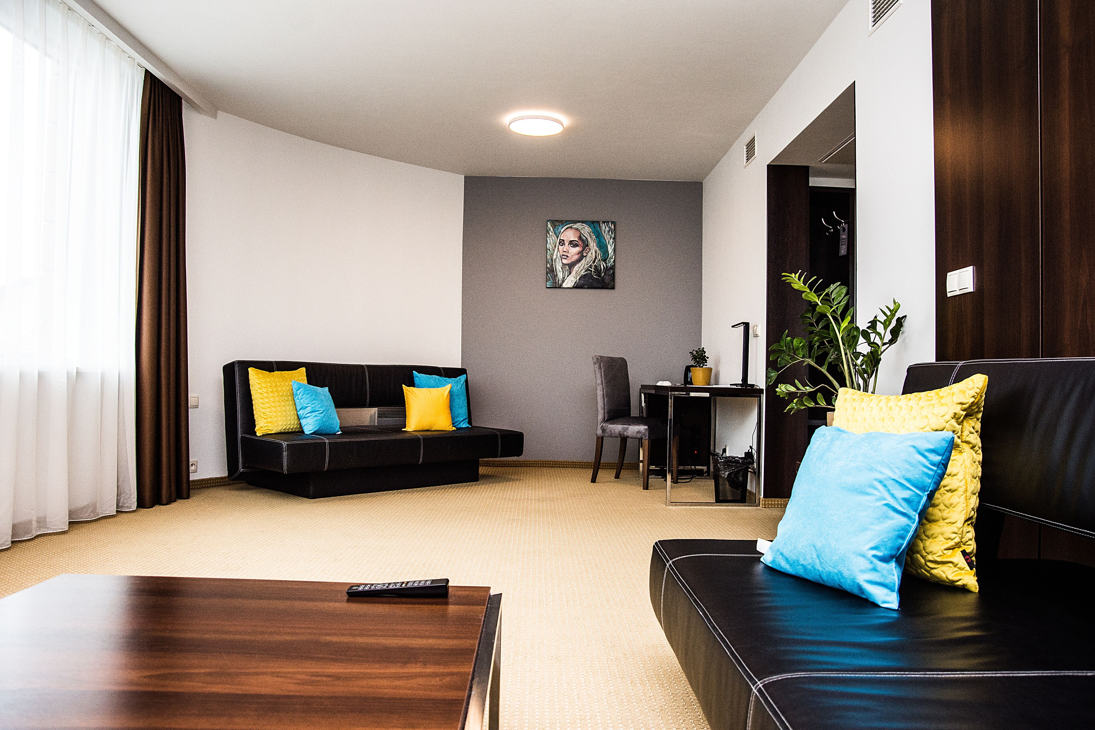 Una sala de estar moderna con un sofá negro, una mesa de centro de madera y un cuadro en la pared.