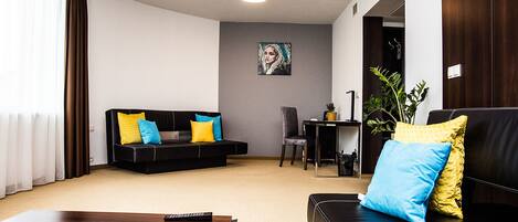 Una sala de estar moderna con un sofá negro, una mesa de centro de madera y un cuadro en la pared.