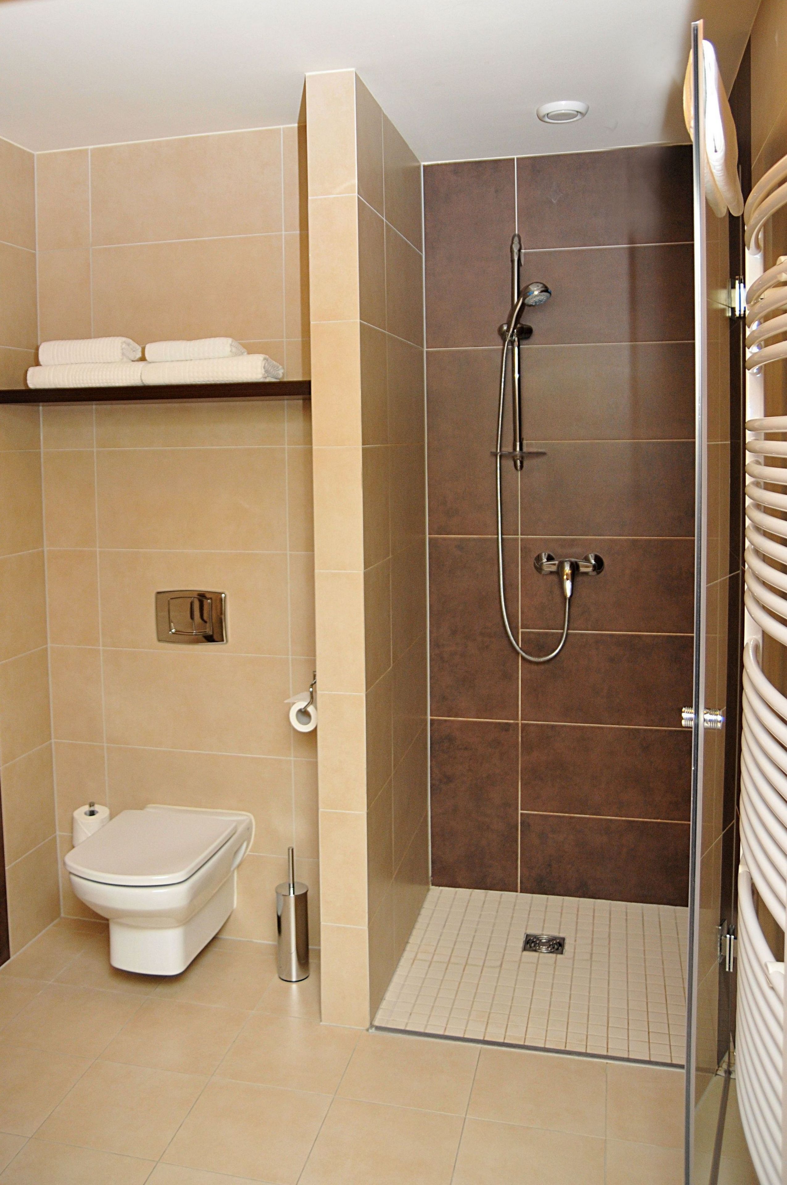 A modern bathroom with a toilet, a shower with a glass door, and a towel rack.