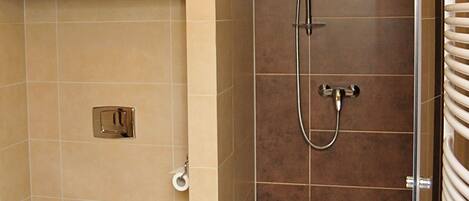 Un baño moderno con inodoro, ducha con puerta de cristal y un perchero para toallas.