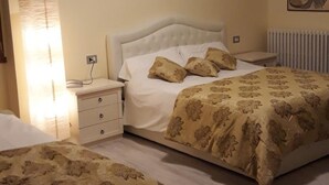 A hotel room with a large bed, a bedside table, a lamp, and a radiator. - San Marino (Laglio)