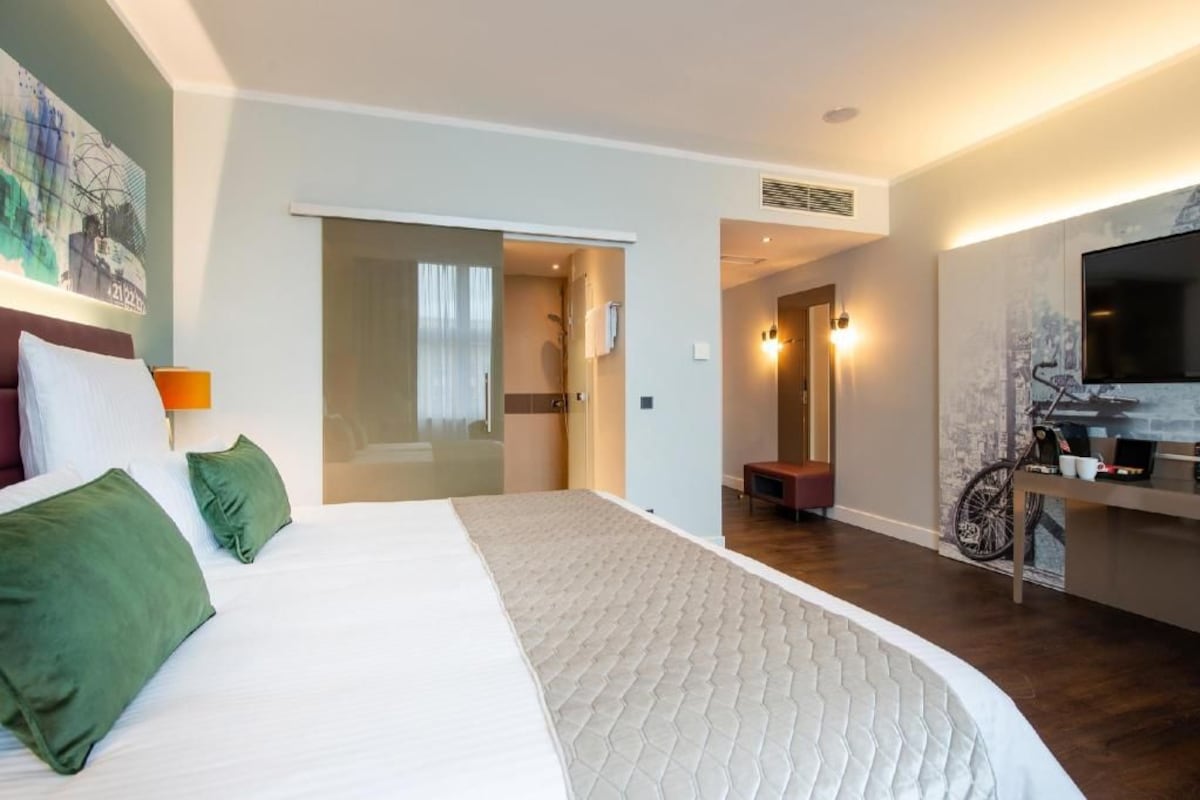 Una habitación de hotel con cama, televisión, bicicleta y baño.