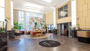 A spacious lobby with a reception desk, seating area, and large windows. - Leonardo Royal Hotel Berlin Alexanderplatz (Berlin)