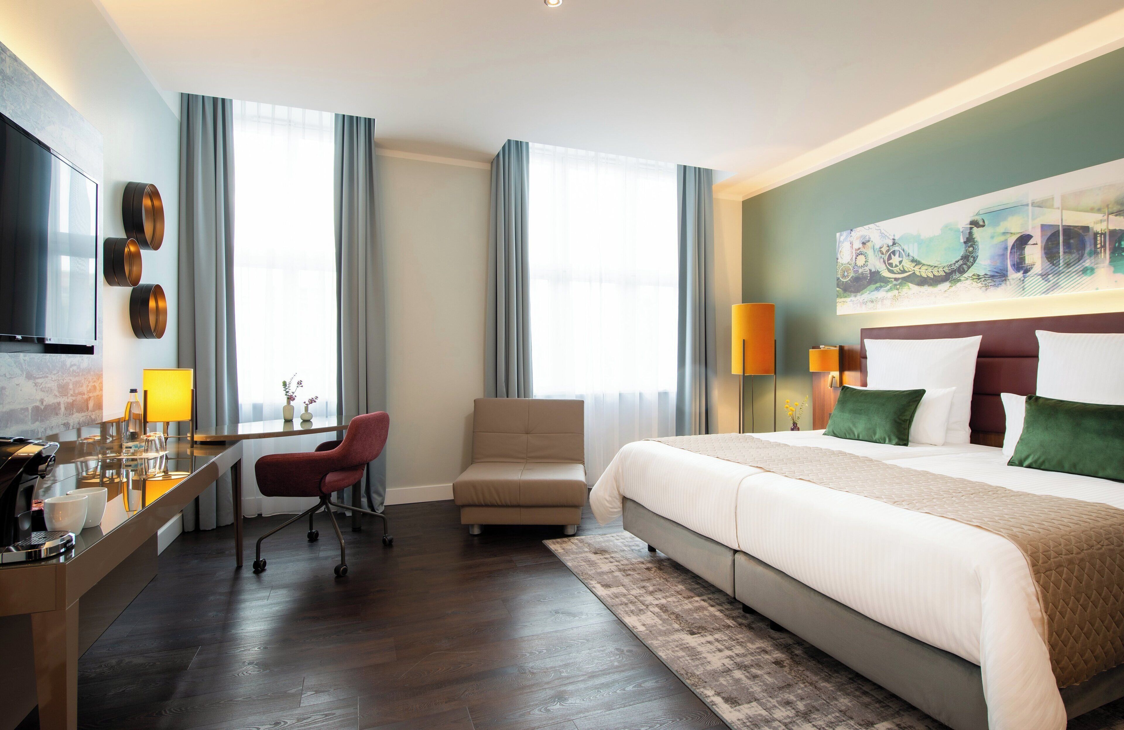 A hotel room with a large bed, a desk with a chair, a TV, and a painting on the wall.