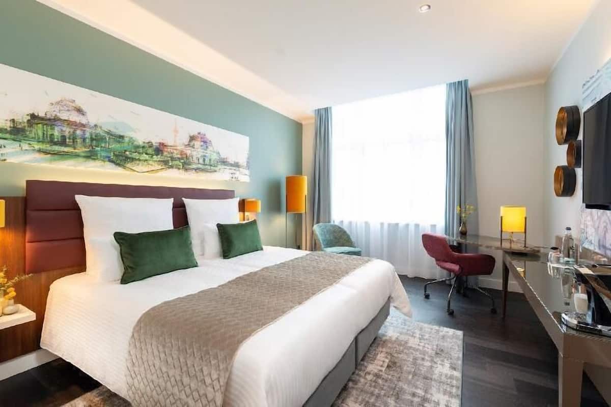 Una habitación de hotel con una cama grande, un escritorio, una silla y un televisor.
