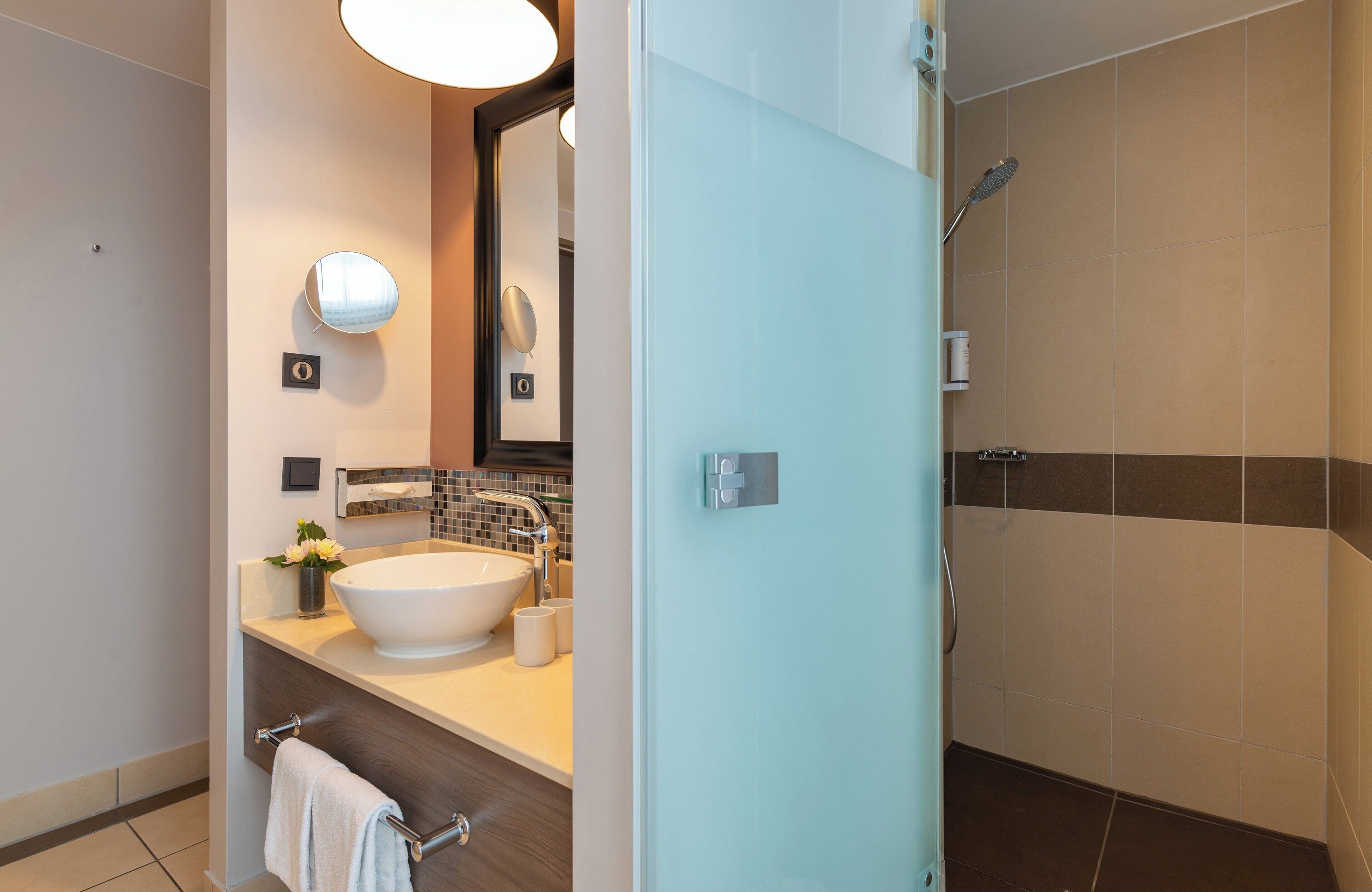 A modern bathroom with a large sink, mirror, and shower.