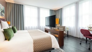 A hotel room with a large bed, a TV, a desk, and a chair. - Leonardo Royal Hotel Berlin Alexanderplatz (Berlin)