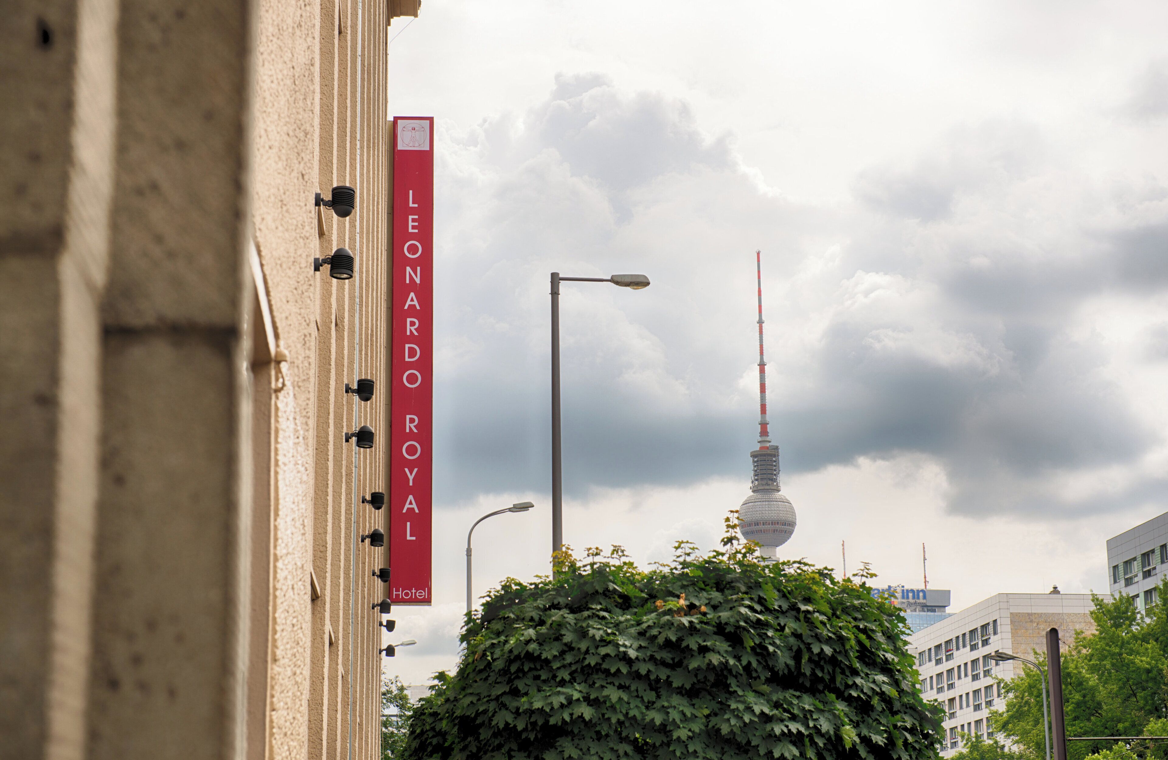 A hotel sign with the name "Leonardo Royal Hotel" and a view of a tower in the background.
