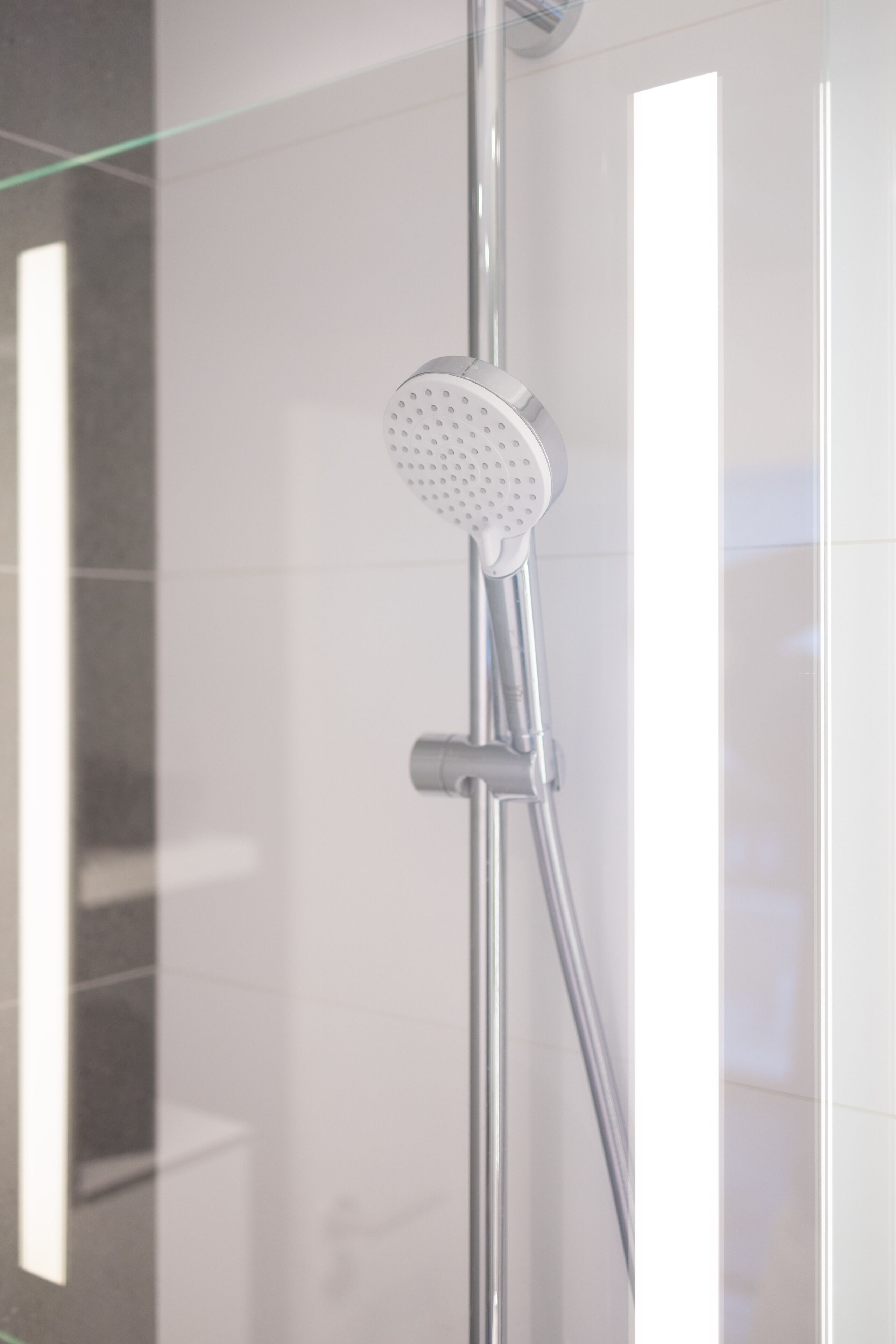 Una ducha moderna con cabezal de ducha de mano y un cabezal de ducha tipo lluvia vertical.