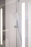 Una ducha moderna con cabezal de ducha de mano y un cabezal de ducha tipo lluvia vertical.