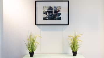 Una fotografía enmarco en una pared, dos plantas en macetas sobre un estante.