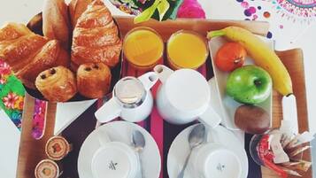 A breakfast tray with croissants, juice, fruit, and a teapot.