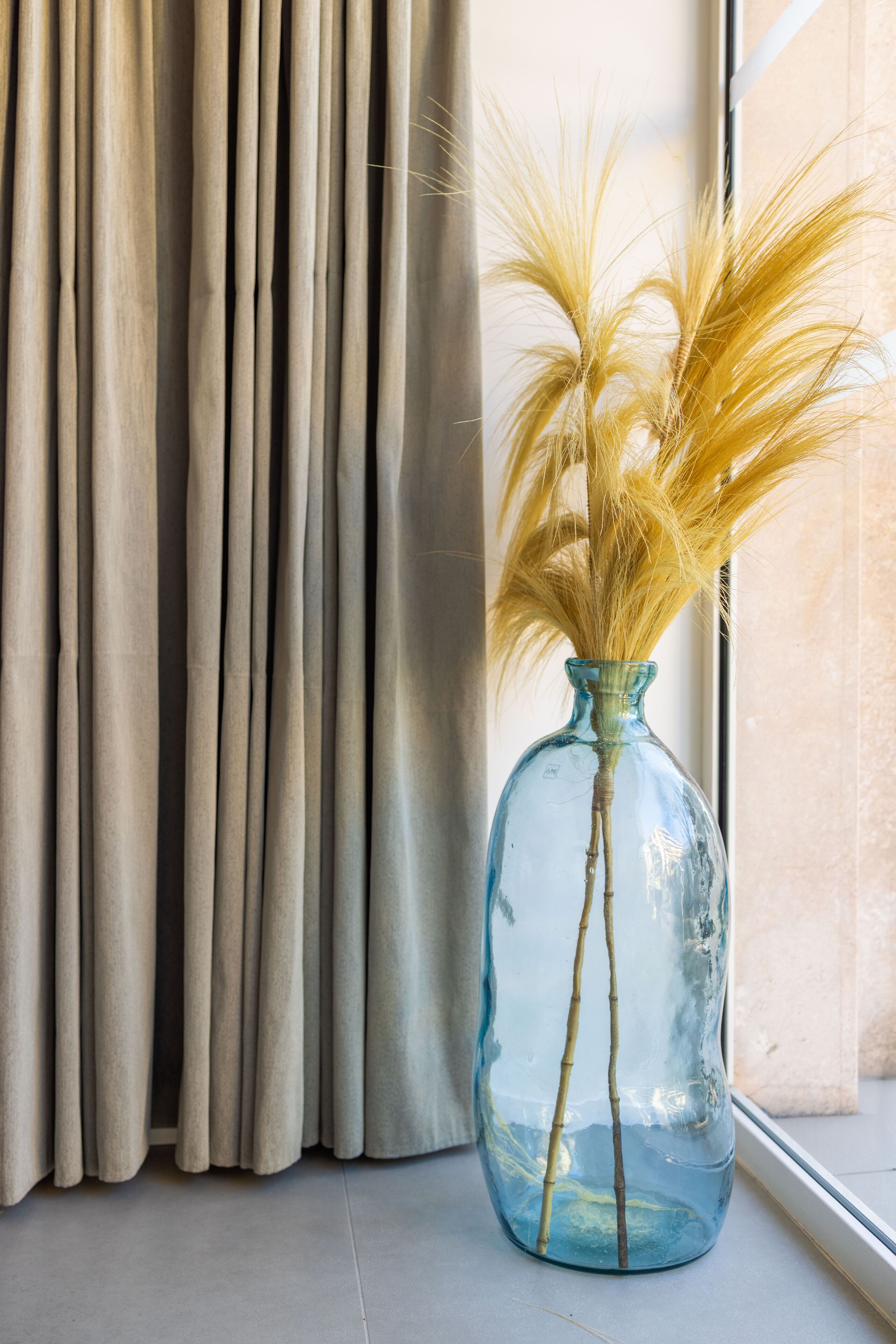 A window with beige curtains and a clear view of the outside.