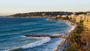 Un paisaje urbano costero con un rompeolas rocoso, un paseo marítimo y edificios a lo largo de la costa.